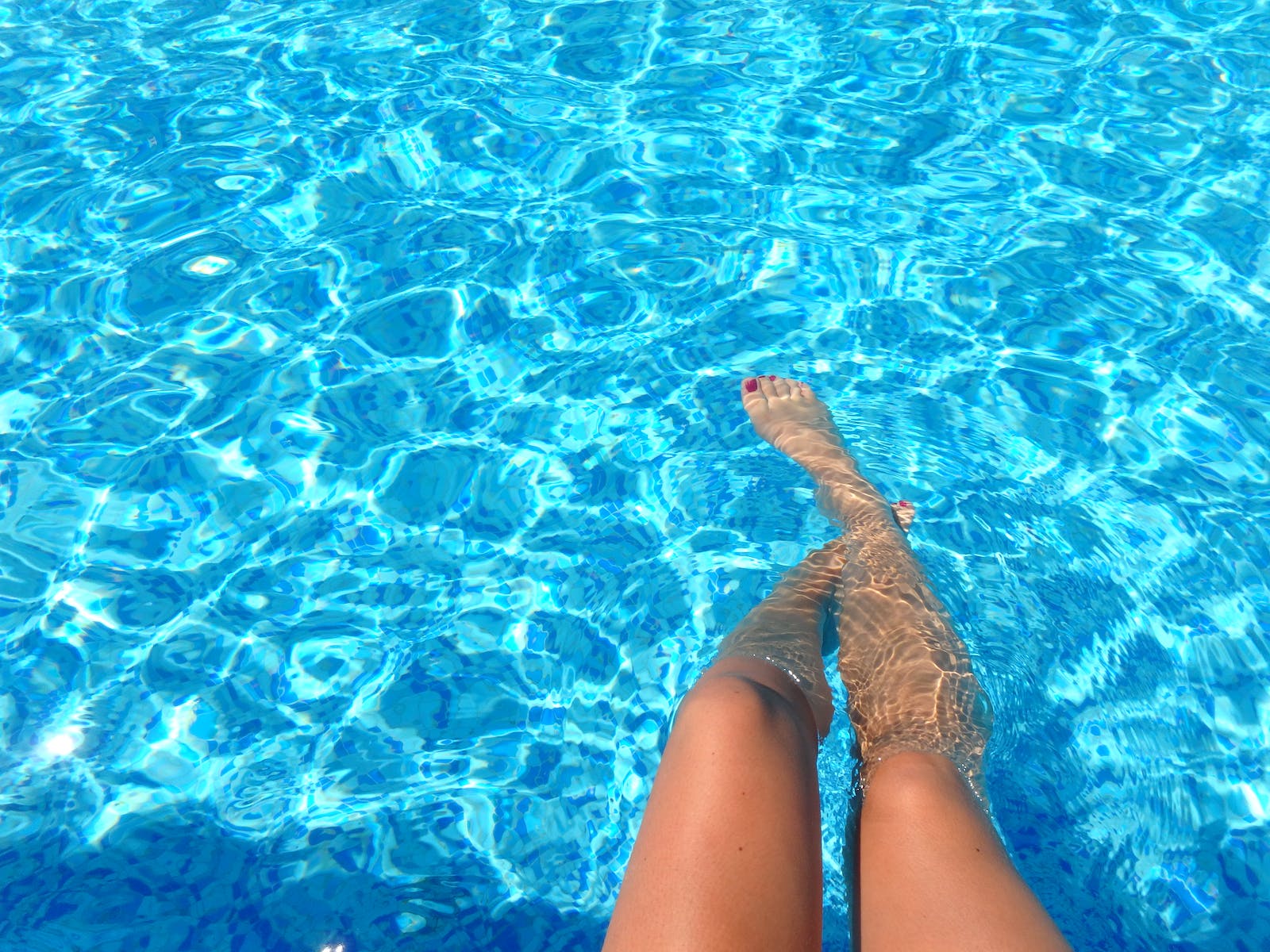 eau transparente d'une piscine avec une femme les pieds dans l'eau
