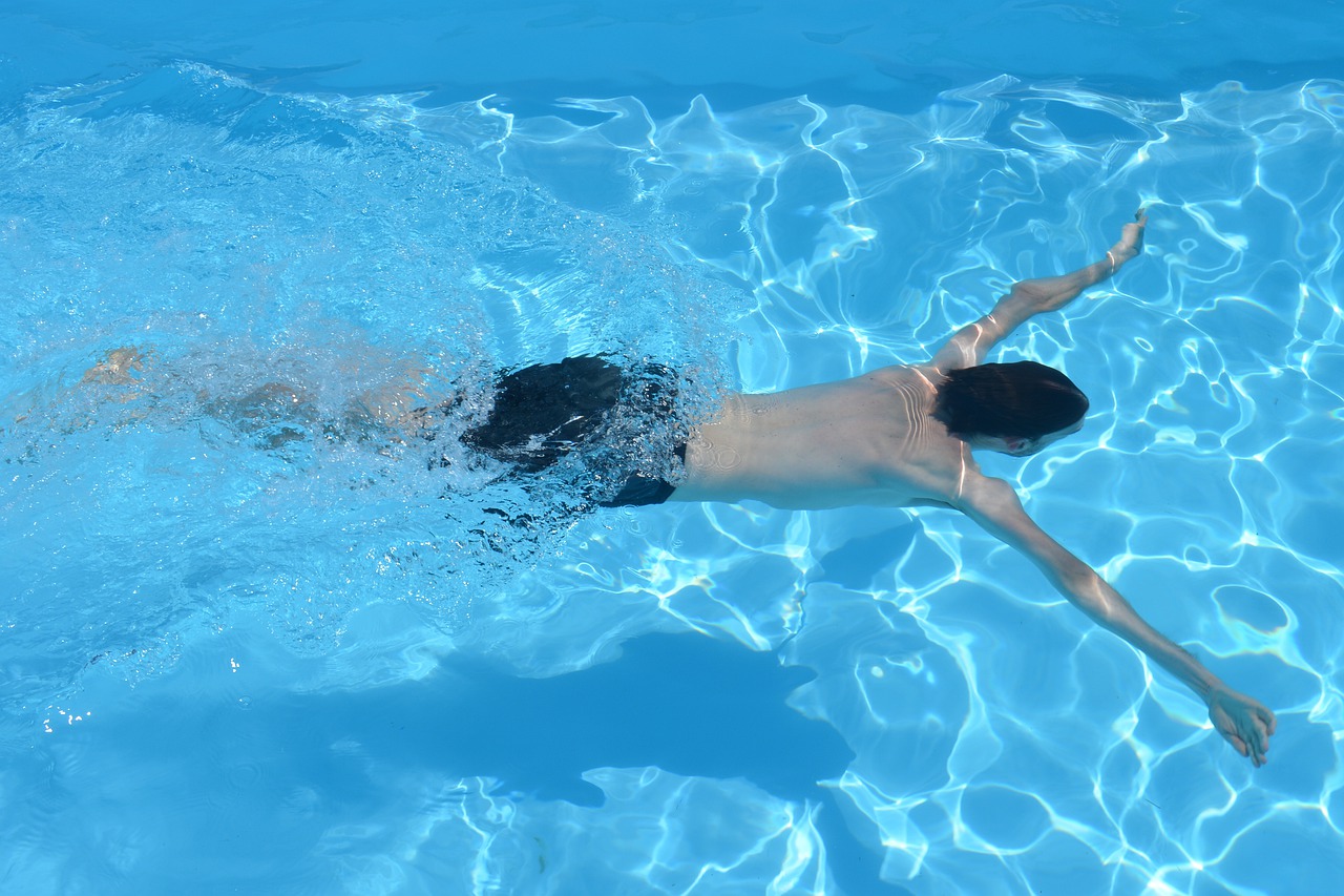 homme dans une piscine qui nage sous l'eau