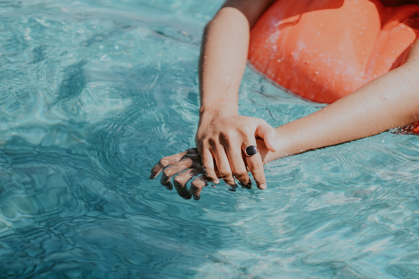 mains d'une femme appuyée sur une bouée dans une piscine